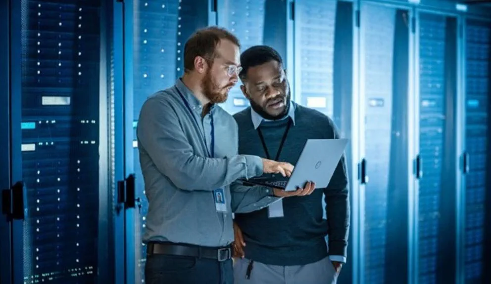 man showing something to another man on laptop man showing something to another man on laptop