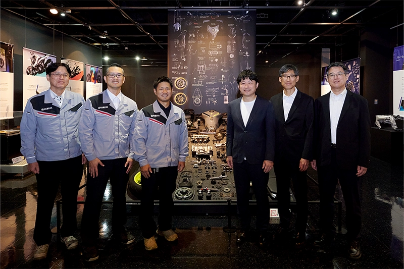 ヤマハ発動機およびAKKODiS 社員6名の展示物を背景に並ぶ集合写真