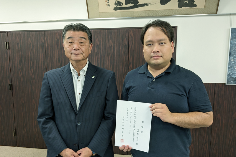 並んで立つ男性二人。一人が委嘱状を手に持っている