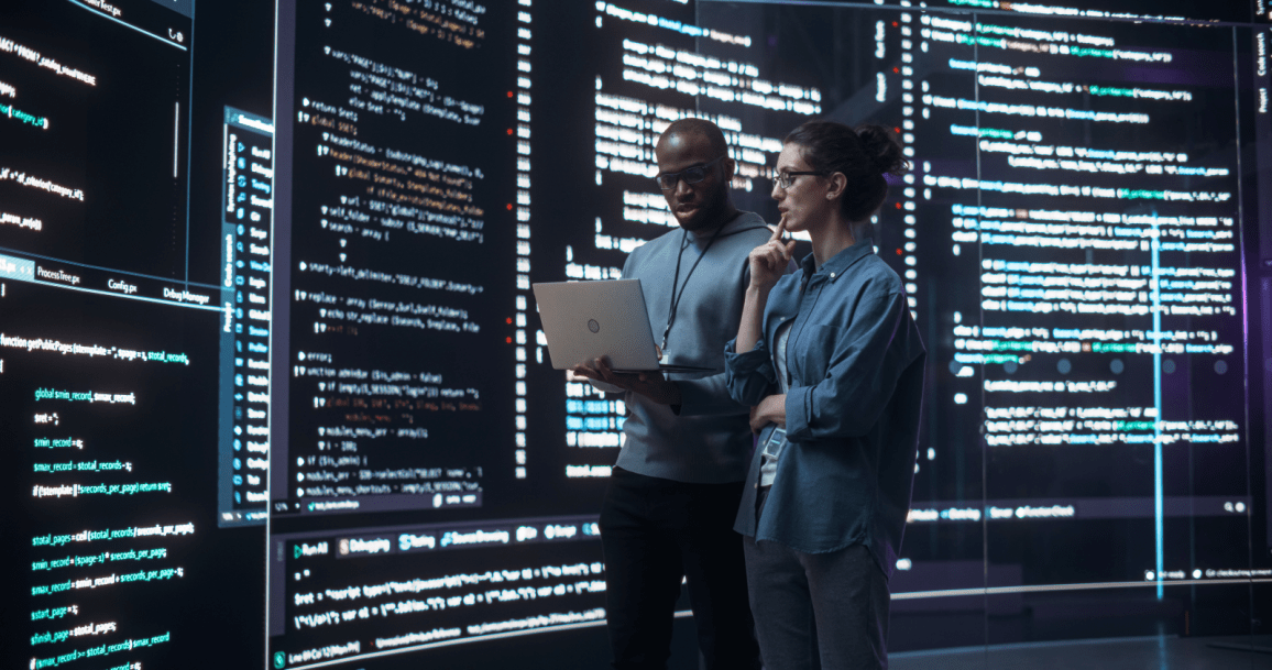 Two people standing in front of huge computer screens