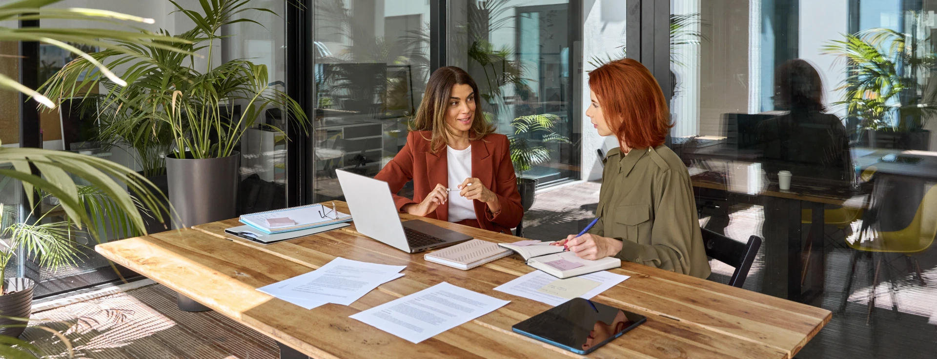 Professional ladies employee and manager having conversation using laptop at work