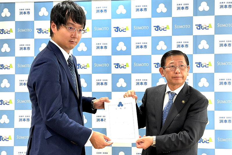 洲本市より委嘱状授与。2人の男性が委嘱状をもっている。